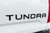 Close-up of a 'Tundra' logo on a white vehicle. 2014-2021