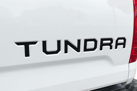 Close-up of a 'Tundra' logo on a white vehicle. 2014-2021