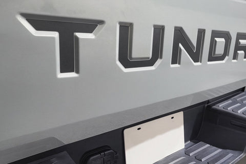 Close-up of a 'Tundra' logo on a vehicle bed cover. 2022-2026 Toyota Tundra