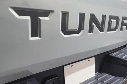 Close-up of a 'Tundra' logo on a vehicle bed cover. 2022-2026 Toyota Tundra