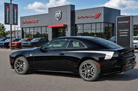 Black 2026 Dodge Charger Sixpack with side body vinyl graphics and stripes parked in front of a Dodge dealership