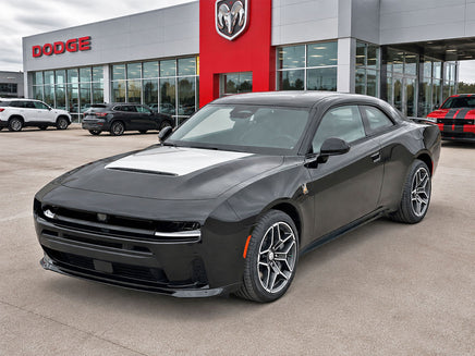 Gray Dodge car parked in front of a Dodge dealership